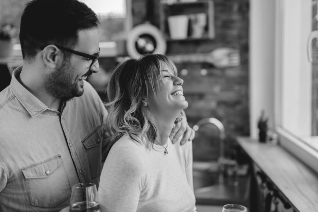 Happy couple having fun and laughing while talking in the kitchen.